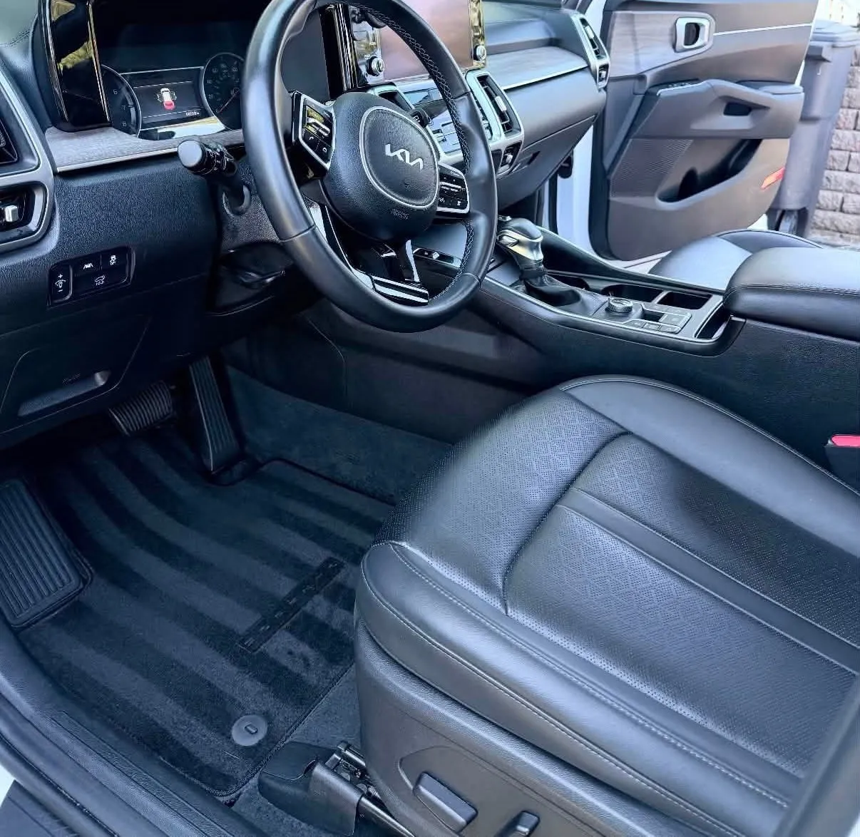 Kia Sportage interior after detailing, showing a clean dashboard, console, leather seat and vacuumed floor mats.